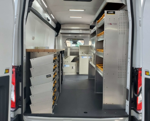 A van upfit with shelves and storage drawers from an outside rear view